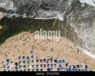 Vue de dessus de la plage de Drini à Gunungkidul, Yogyakarta, Indonésie avec beaucoup de gens et de nombreuses planches de surf colorées. Banque D'Images