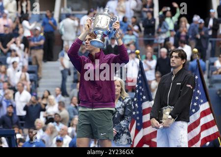 Le vainqueur Jannik Sinner, de l'Italie, célèbre la victoire pendant que Taylor Fritz, des États-Unis, regarde pendant la cérémonie du trophée de la 39 finale masculine du jour 14 de l'US Open, tournoi de tennis du Grand Chelem 2024, le 8 septembre 2024 au Centre national de tennis USTA Billie Jean King à Flushing Meadows, Queens, New York, États-Unis Banque D'Images