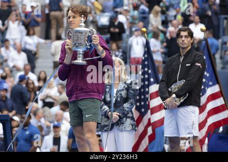 Le vainqueur Jannik Sinner, de l'Italie, célèbre la victoire pendant que Taylor Fritz, des États-Unis, regarde pendant la cérémonie du trophée de la 39 finale masculine du jour 14 de l'US Open, tournoi de tennis du Grand Chelem 2024, le 8 septembre 2024 au Centre national de tennis USTA Billie Jean King à Flushing Meadows, Queens, New York, États-Unis Banque D'Images