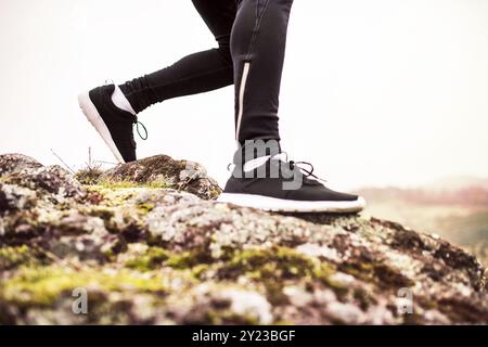 Gros plan sur les jambes du coureur, les pieds avec des chaussures de course durig jogging hors route dans la nature sur sentier de course en terre battue. Banque D'Images