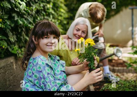 Portrait d'écolière mignonne prenant soin des plantes dans le jardin de l'école pendant à la classe d'éducation durable en plein air. Concept d'apprentissage expérientiel et Banque D'Images