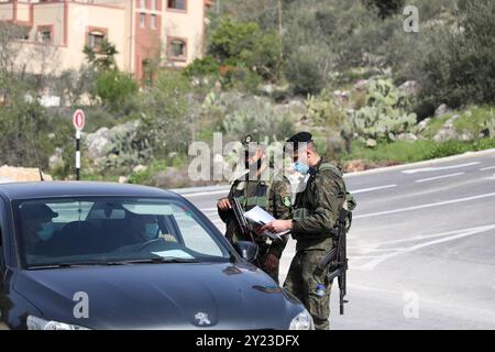 Tulkarem, Cisjordanie, Palestine. 09 mars 2021. Les membres des Forces de sécurité nationales palestiniennes vérifient les véhicules circulant dans la ville de Tulkarem, alors qu’un nouveau confinement est imposé en Cisjordanie pour contenir une nouvelle recrudescence de cas de COVID-19. Malgré un couvre-feu nocturne en place depuis une semaine, il y a eu une forte augmentation des cas de coronavirus parmi les Palestiniens en Cisjordanie. Les restrictions imposées par le confinement actuel comprennent la fermeture d'écoles, d'universités et d'entreprises non essentielles Banque D'Images