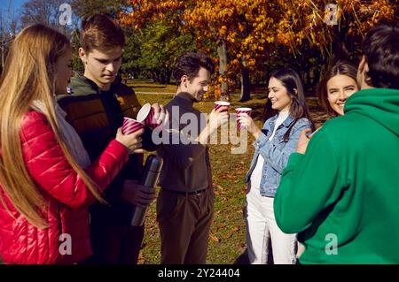 Groupe de meilleurs amis amis parlant et buvant du thé dans des gobelets en papier le jour ensoleillé d'automne. Banque D'Images