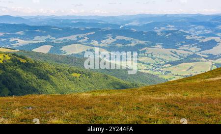 vue dans la vallée rurale lointaine. paysage de campagne montagneux. prairies verdoyantes et collines boisées. beau paysage naturel des carpates Banque D'Images