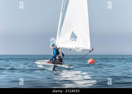Bateau à voile de canot à voile de direction de sportif sur la mer calme Banque D'Images