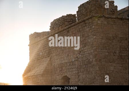 Le soleil couchant jette une lueur chaude sur les murs de pierre altérés d'une forteresse médiévale. Paphos, Chypre Banque D'Images