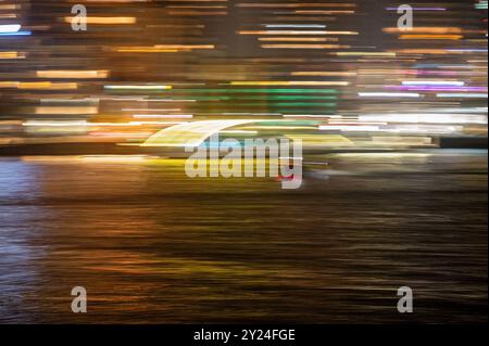 Vitesse de bateau-taxi à travers le port fluvial de la ville la nuit, panoramique flou à grande vitesse Banque D'Images