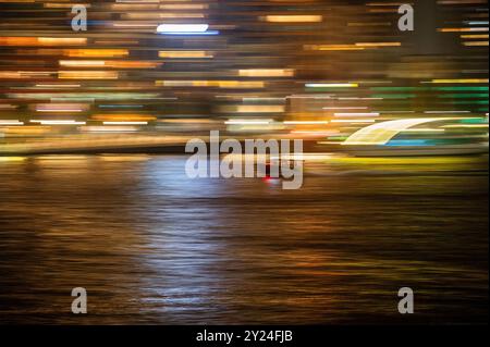 Vitesse de bateau-taxi à travers le port fluvial de la ville la nuit, panoramique flou à grande vitesse Banque D'Images