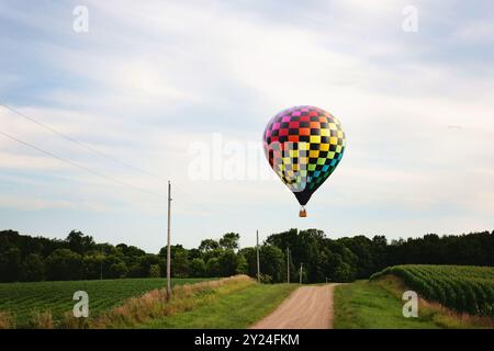 Montgolfière volant à basse altitude au-dessus d'une route de gravier de campagne. Banque D'Images