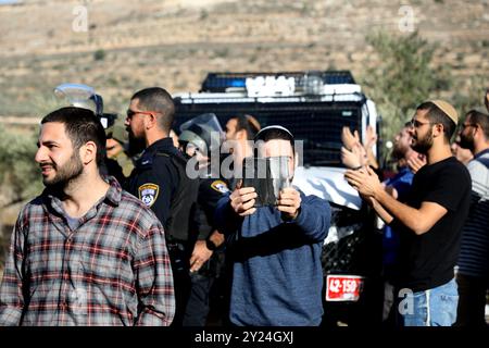 Naplouse, Cisjordanie, Palestine. 28 novembre 2021. Des colons juifs israéliens se rassemblent aux côtés de soldats israéliens dans le village palestinien de Lubban Ash-Sharqiya, au sud de Naplouse. Les colons étaient entrés dans le village alors que certains de ses habitants se rassemblaient pour protester contre les récentes attaques quotidiennes des colons à l’école de Lubban Ash-Sharqiya pour empêcher les élèves d’accéder à l’école et à leurs cours. Les colonies judéo-israéliennes continuent de s'étendre en Cisjordanie et à Jérusalem-est, bien qu'elles constituent une violation du droit international Banque D'Images