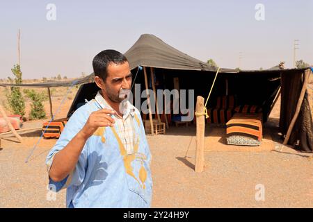 Camp nomade avec dromadaires et chauffeur de chameaux dans la campagne désertique près du moyen Atlas au Maroc. Maroc, Afrique du Nord. Crédit : photo par Hug Banque D'Images