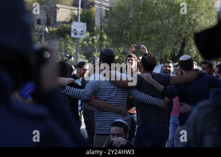 Naplouse, Cisjordanie, Palestine. 28 novembre 2021. Des colons juifs israéliens se rassemblent aux côtés de soldats israéliens dans le village palestinien de Lubban Ash-Sharqiya, au sud de Naplouse. Les colons étaient entrés dans le village alors que certains de ses habitants se rassemblaient pour protester contre les récentes attaques quotidiennes des colons à l’école de Lubban Ash-Sharqiya pour empêcher les élèves d’accéder à l’école et à leurs cours. Les colonies judéo-israéliennes continuent de s'étendre en Cisjordanie et à Jérusalem-est, bien qu'elles constituent une violation du droit international Banque D'Images