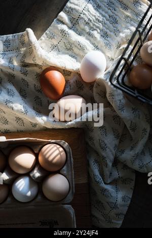 Oeufs naturels dans un panier et carton, placés sur un tissu à motifs Banque D'Images