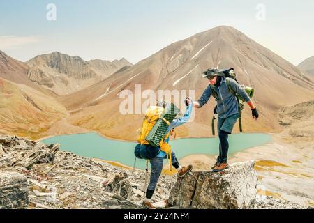 Couple travail d'équipe ensemble aide sur les voyages de défi. Main de secours entre deux grimpeurs. L'homme donne des instructions à la femme randonneuse. Groupe de travail d'équipe de touristes le Banque D'Images
