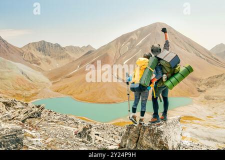 Couple de randonneurs atteignant le sommet célèbrent les mains sur le sommet de joie panorama caucase en plein air. Couple victorieux aventuriers amis trek ou randonnée trave Banque D'Images