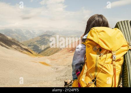 Vue rapprochée depuis le dos femme méconnaissable avec sac à dos jaune élégant avec flacon sortant de la poche latérale. Bannière d'espace de copie de maquette. W Banque D'Images