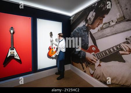 Londres, Royaume-Uni. 9 septembre 2024. Un technicien présente (R) 'an Epiphone les Paul Standard Electric Guitar, possédée et utilisée par Noel Gallagher pendant les sessions précédant l'enregistrement final d'Oasis' 1994 premier album 'Definally Maybe' at Sawmills Studio' par Noel Gallagher / Oasis (est. £60 000 - 80,000) avec la guitare Flying V Noel Gallagher lors d'un aperçu aux galeries Sotheby's New Bond Street de leur première vente aux enchères en ligne populaire culture. Les offres sont clôturées le 12 septembre. Credit : Stephen Chung / Alamy Live News Banque D'Images