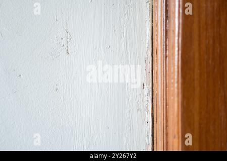 Vue rapprochée d'un mur texturé bleu clair rencontrant un cadre en bois, mettant en valeur le contraste entre la surface lisse du mur et le grain naturel du bois Banque D'Images