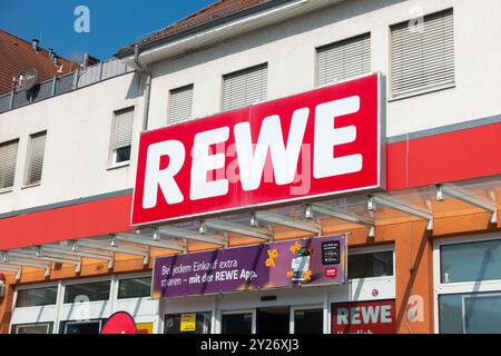 Logo REWE au-dessus de l'entrée du supermarché Allemagne Europe vue extérieure d'une vitrine de supermarché REWE avec signalisation et bannière promotionnelle Banque D'Images