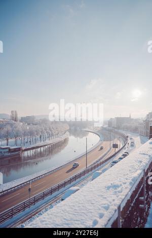 City Autobahn avec des voitures près d'une rivière vue d'en haut un jour d'hiver ensoleillé où le paysage urbain est couvert de neige et de glace Banque D'Images