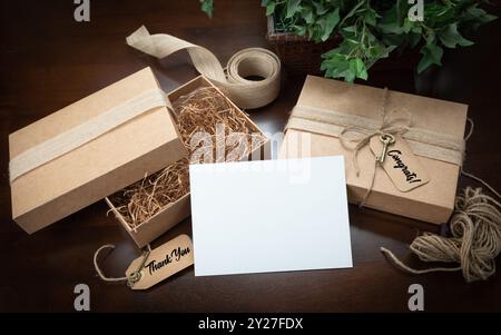 Boîtes d'emballage cadeau maquette avec ficelle de jute, carte de remerciement et de félicitations et étiquettes avec petite clé sur la surface en bois. Banque D'Images