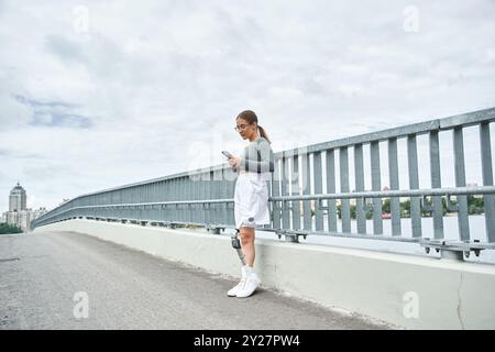 Une jeune femme en vêtements de sport profite activement de son entraînement en plein air tout en utilisant un smartphone. Banque D'Images