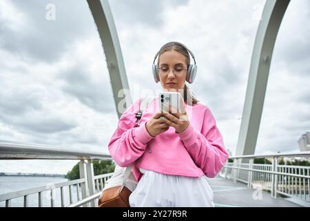 Une jeune femme utilisant un smartphone et écoutant de la musique dans des écouteurs Banque D'Images