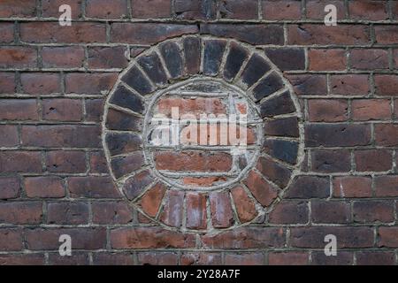 Un mur de briques avec un cercle. Vieux mur de briques teintées d'un bâtiment industriel, hublot rond briqué, espace de copie créatif, aspect horizontal Banque D'Images
