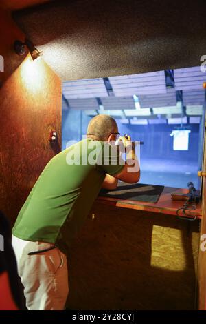 Tir dans le tableau de bord des armes à canon court. Un homme vise une cible avant de tirer un pistolet. Banque D'Images