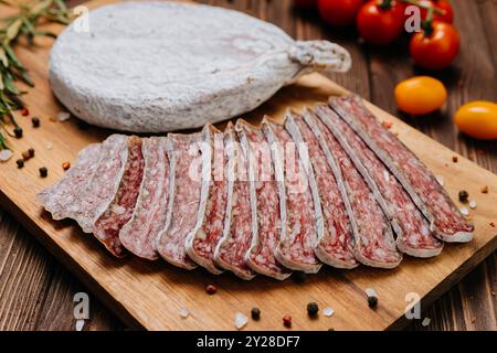 Gros plan de salami séché en tranches à bord, idéal pour les présentations gastronomiques et de charcuterie Banque D'Images