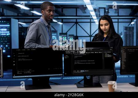 Techniciens du centre de données utilisant des périphériques pour vérifier les problèmes de performances du serveur dus à une utilisation élevée du processeur. Les membres du personnel de la batterie de serveurs corrigent les erreurs de mémoire insuffisante ralentissant le matériel Banque D'Images