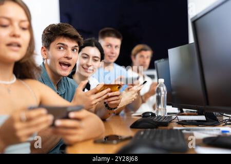 Jeune développeur enthousiaste utilisant le téléphone mobile lors de la présentation de démarrage INFORMATIQUE Banque D'Images