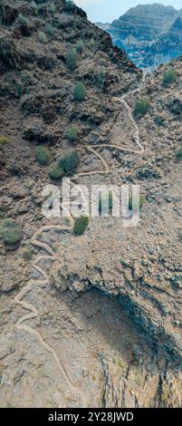 Vue aérienne du sentier à travers les montagnes jusqu'à la plage de Guigui, plage de sable noir immaculé, Gran Canaria. Espagne. Sentier pittoresque Banque D'Images