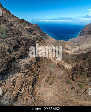 Vue aérienne du sentier à travers les montagnes jusqu'à la plage de Guigui, plage de sable noir immaculé, Gran Canaria. Espagne. Sentier pittoresque Banque D'Images