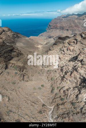 Vue aérienne du sentier à travers les montagnes jusqu'à la plage de Guigui, plage de sable noir immaculé, Gran Canaria. Espagne. Sentier pittoresque Banque D'Images