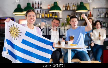 Les fans du drapeau de l'Uruguay célèbrent la victoire de leur équipe préférée au bar à bière Banque D'Images