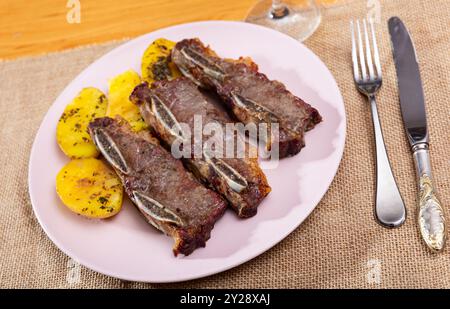 Sur des côtes de bœuf grillées blanches garnies de pommes de terre frites Banque D'Images