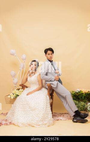 élégant couple masculin et féminin pose assis sur des chaises longues tout souriant gâté regardant vers l'avant intimement en intérieur photo de gros plan. couple weddin Banque D'Images