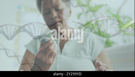 Image de brins d'adn sur une femme afro-américaine âgée utilisant un glucomètre Banque D'Images