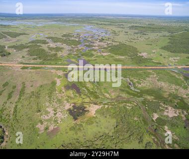 Vue aérienne de Transpantaneira route de terre traversant un lagon au-dessus d'un petit pont dans le paysage typique de North Pantanal Wetlands, Mato Grosso, Brazi Banque D'Images