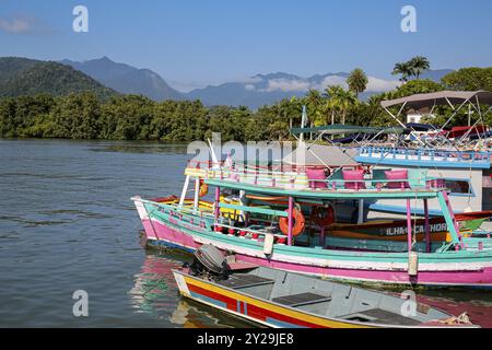 Vue sur les bateaux de visite colorés dans l'eau qui attendent les touristes sur un quai, avec des montagnes vertes en arrière-plan, Paraty, Brésil, patrimoine mondial de l'UNESCO Banque D'Images