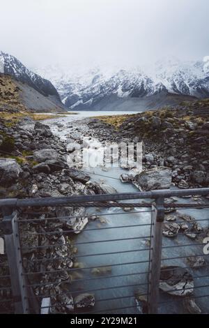 Ruisseau traverse un paysage rocheux au milieu des montagnes enneigées, Hooker Valley Track, Nouvelle-Zélande, Océanie Banque D'Images