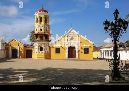 Vue sur la belle église historique Santa Barbara (Iglesia de Santa Barbara) et la place (plaza) en partie dans l'ombre, Santa Cruz de Mompox, la lumière du soleil et blu Banque D'Images