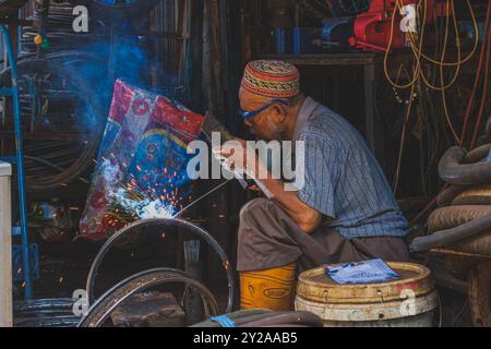 Balikpapan, Indonésie - 26 juin 2024. le vieux soudeur fait une activité de soudage devant son ancien atelier de bois. Banque D'Images