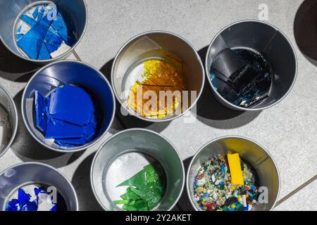 Les fragments de verre colorés pour la fusion sont triés dans de petits récipients en métal, photo en gros plan avec mise au point sélective Banque D'Images