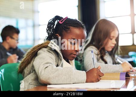 Fille, écriture et pensée avec livre en classe pour l'apprentissage, le développement et la résolution de problèmes pour le progrès. Écoliers, ordinateur portable et étudier avec Banque D'Images