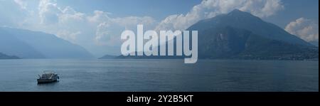 Lac et alpes de Varenna sur les rives du lac de Côme, Italie. Une belle vue sur, les rives de nuages et les crêtes de montagne silhouettées dans la brume d'un bateau. Banque D'Images