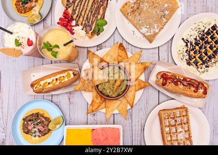 Un ensemble d'apéritifs et de plats sucrés, de crème glacée et de boissons sur une table blanche Banque D'Images