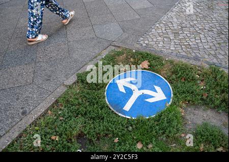 02.09.2024, Berlin, Allemagne, Europe - Un piéton marche par un panneau de signalisation avec des flèches de direction qui se trouve sur le sol sur Kurfuerstendamm. Banque D'Images