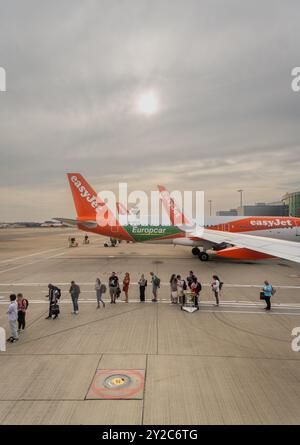 Des gens faisant la queue pour embarquer sur un vol Easyjet sur la piste photographiée depuis la fenêtre du hublot de cabine Banque D'Images